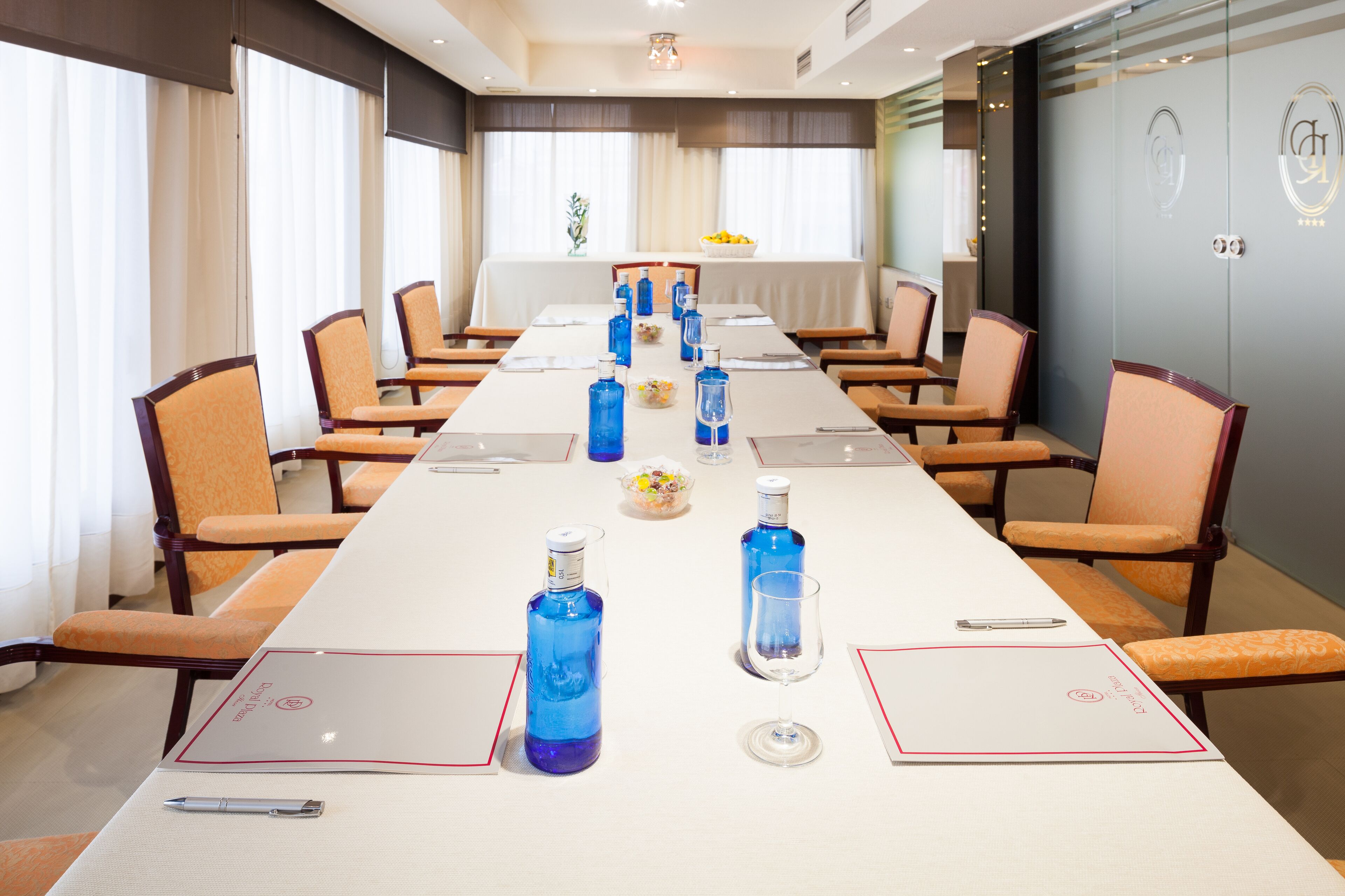 A conference room with a long table, chairs, and amenities like water bottles and a glass.