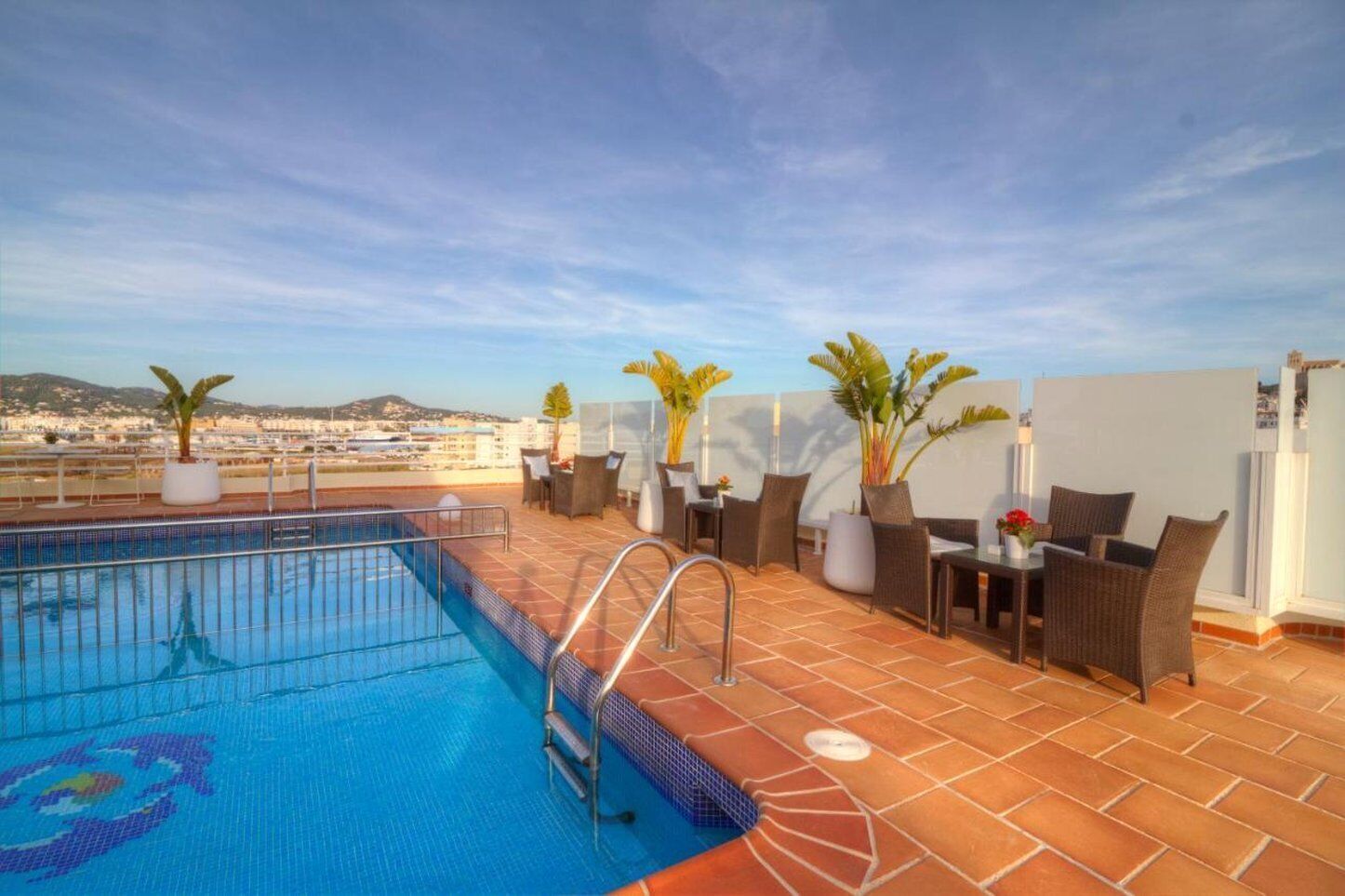 A rooftop pool area with a clear view of the cityscape in the background.