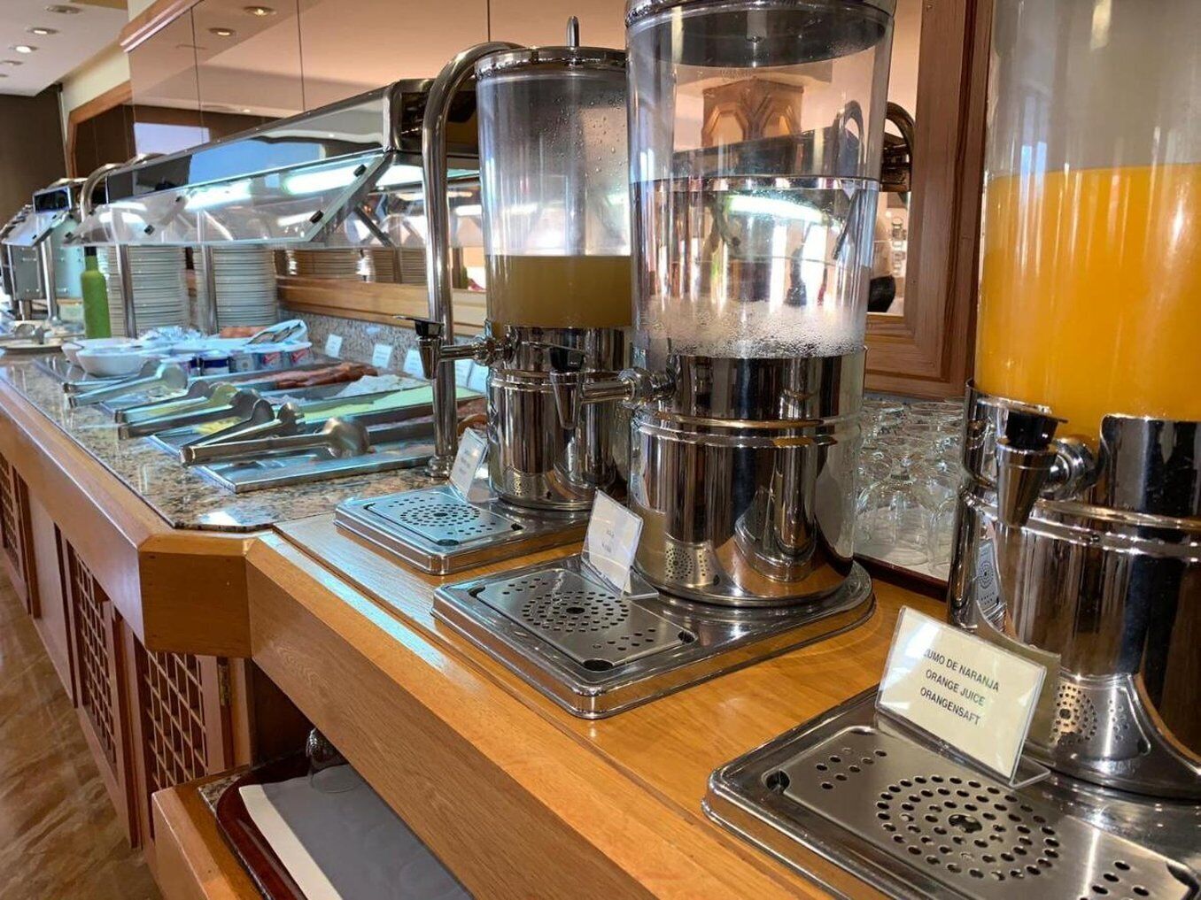 A buffet bar with various food and drink dispensers, including a coffee machine and a juice dispenser.