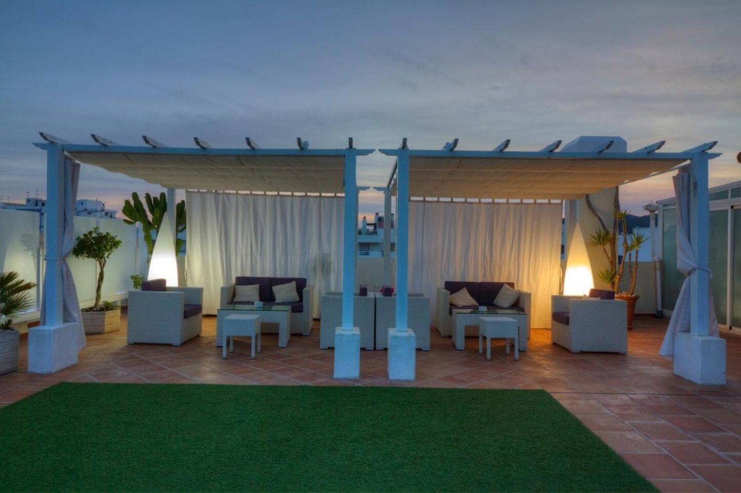 A rooftop terrace with a pergola, outdoor seating, and potted plants.