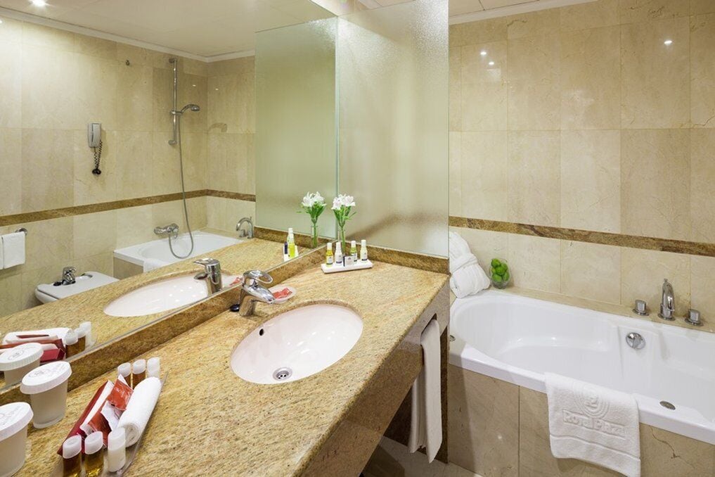 A bathroom with two sinks, a bathtub, and a large mirror.