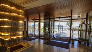 Un vestíbulo con un gran elemento decorativo iluminado, una recepción y vistas al exterior.