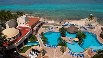 A resort with multiple swimming pools, a beach, and a large building with a red roof.
