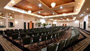 A conference room with rows of chairs, a patterned carpet, and chandeliers.