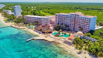 A resort with a large building, a swimming pool, and a beach.
