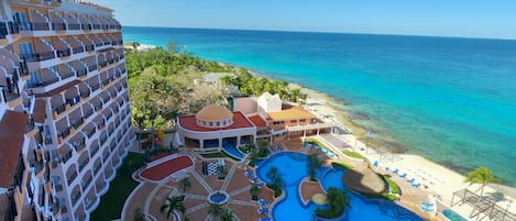 Um resort com uma piscina grande, acesso à praia e vista para o oceano.