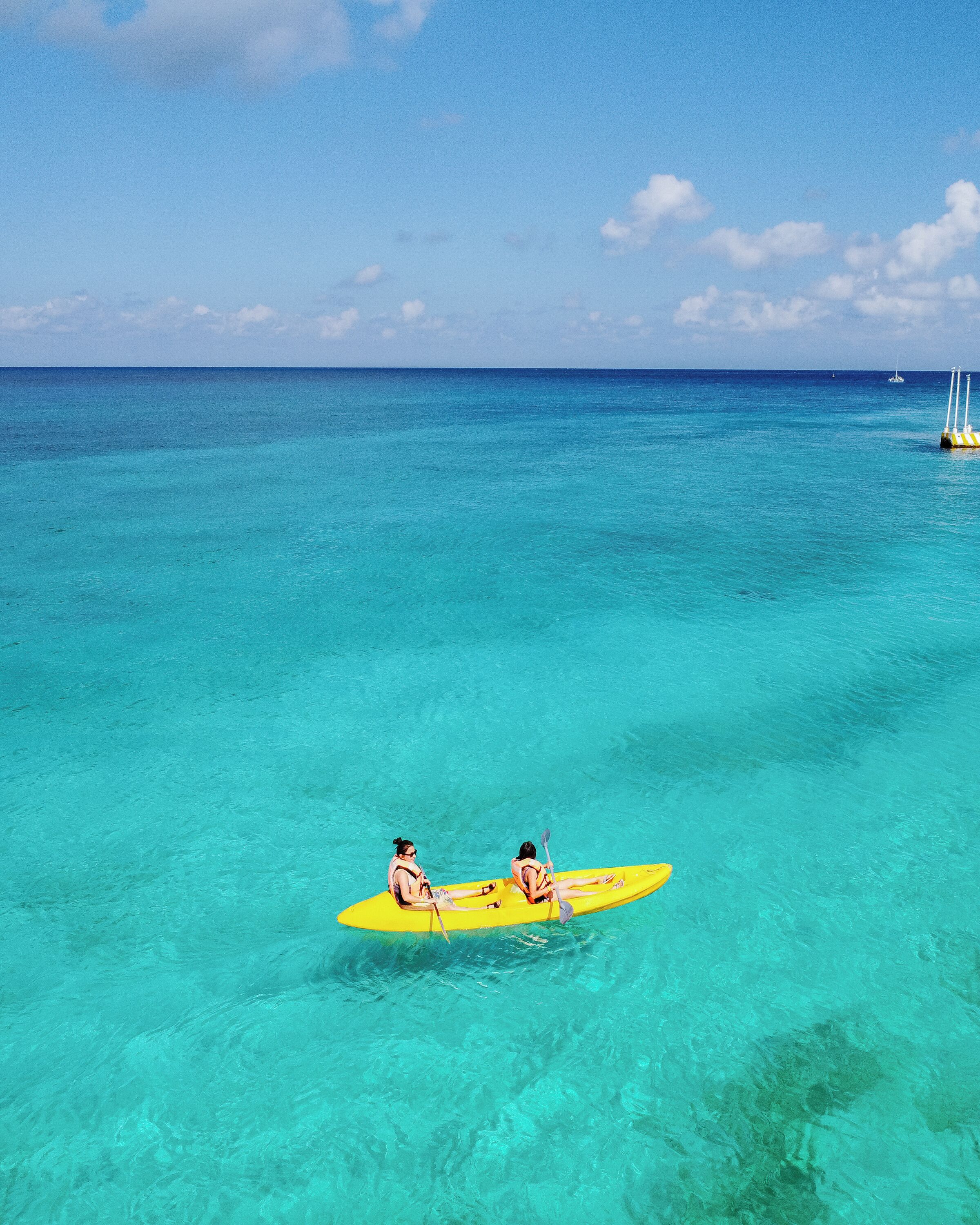 Dos personas en un kayak amarillo en aguas turquesas cristalinas.