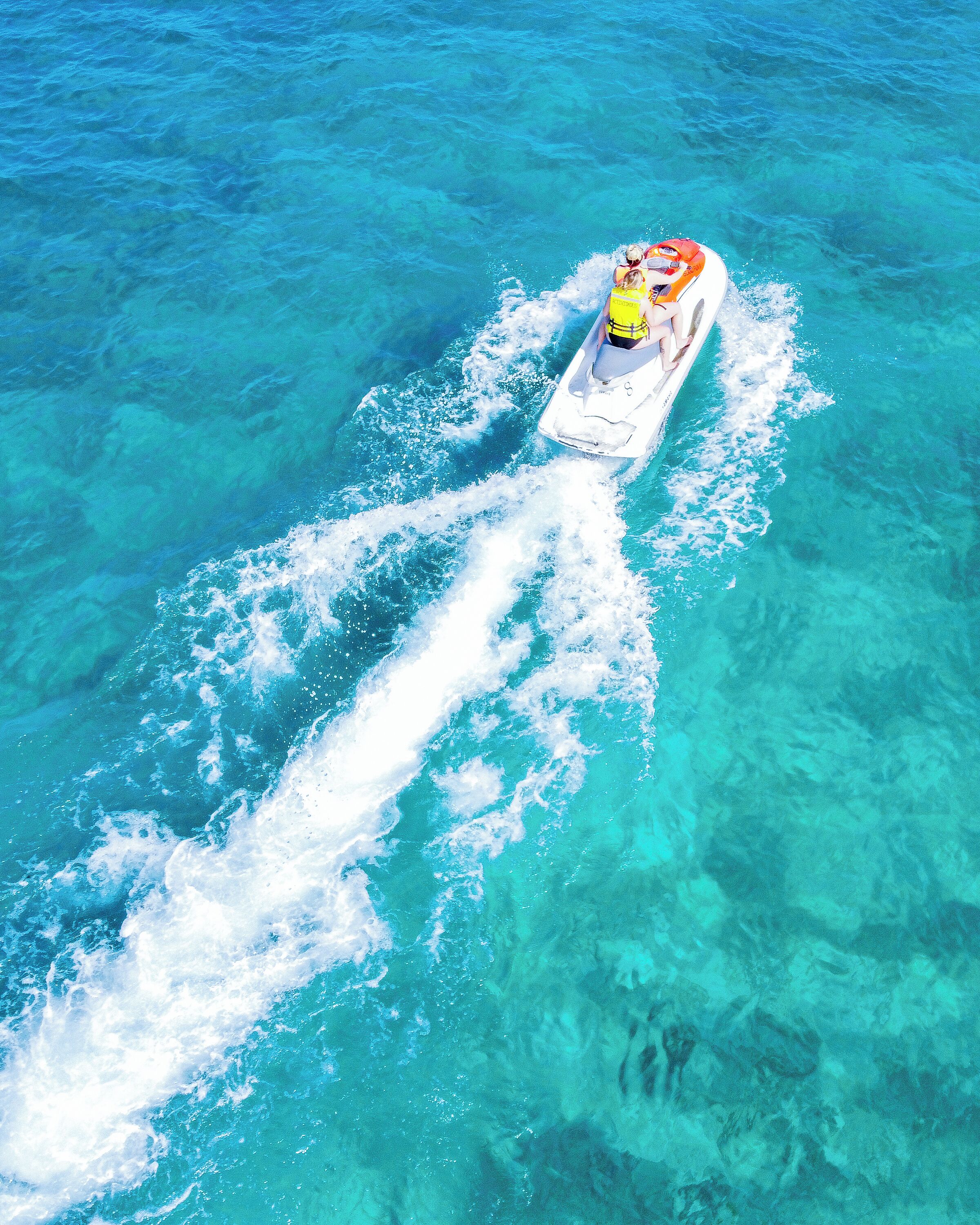 A clear blue water body with a boat creating a wake.