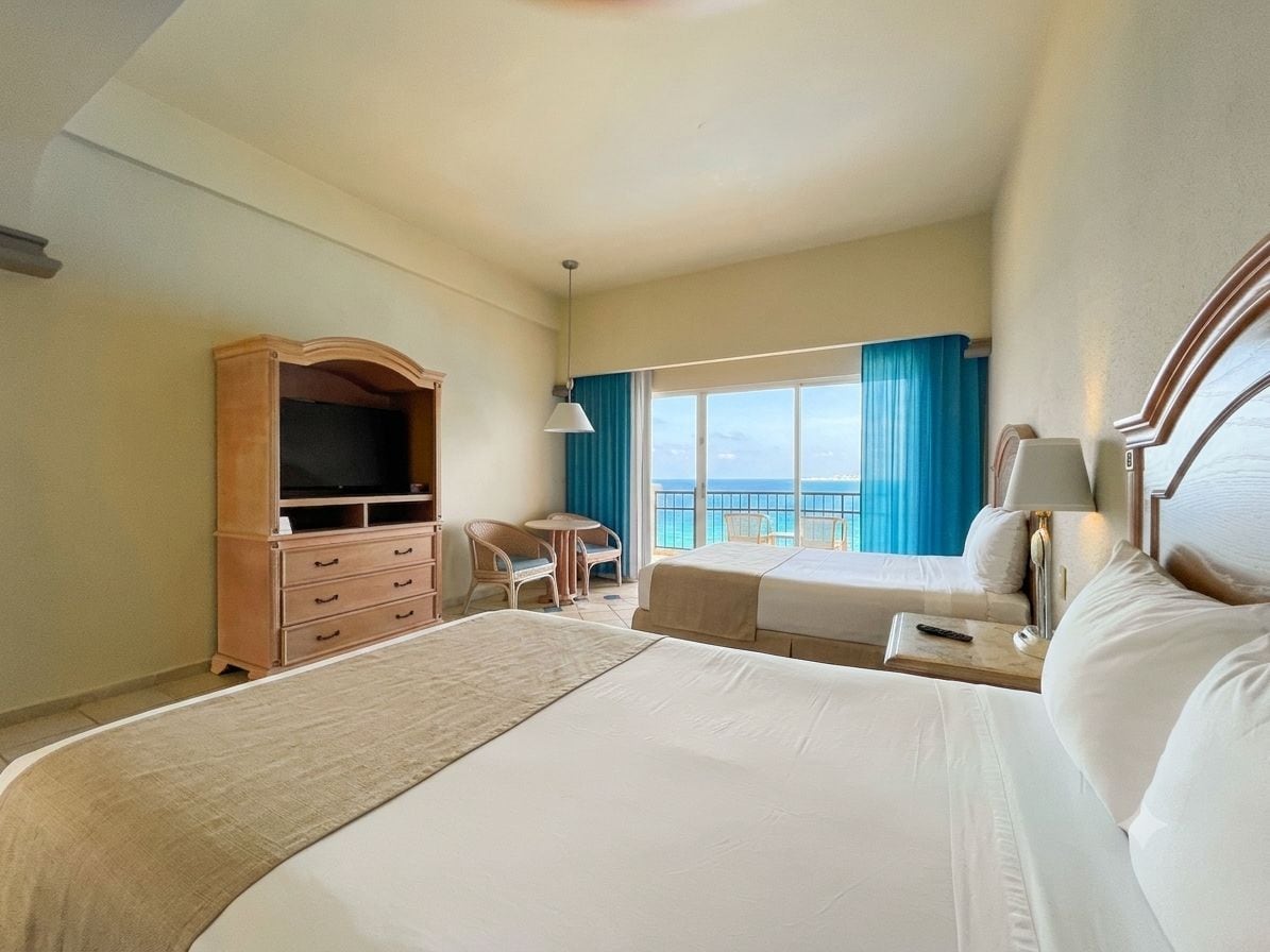 Une chambre d’hôtel avec deux lits, un bureau, une télévision et un balcon avec vue.