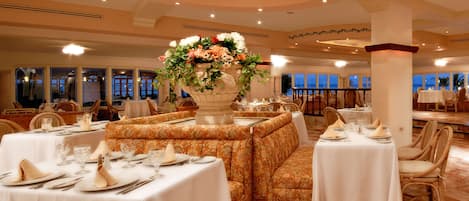 A restaurant with round tables, booths, and a large floral centerpiece.