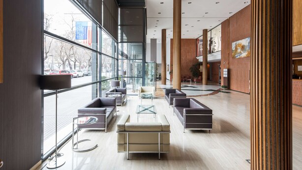 Un hall d’entr ée spacieux, doté de meubles modernes, de grandes fenêtres et offrant une vue sur la rue.