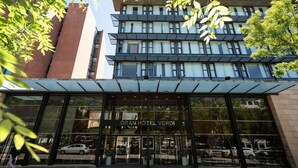 L’entrée d’un hôtel, avec une façade moderne en verre et une enseigne indiquant « GRAN HOTEL VERDI ».