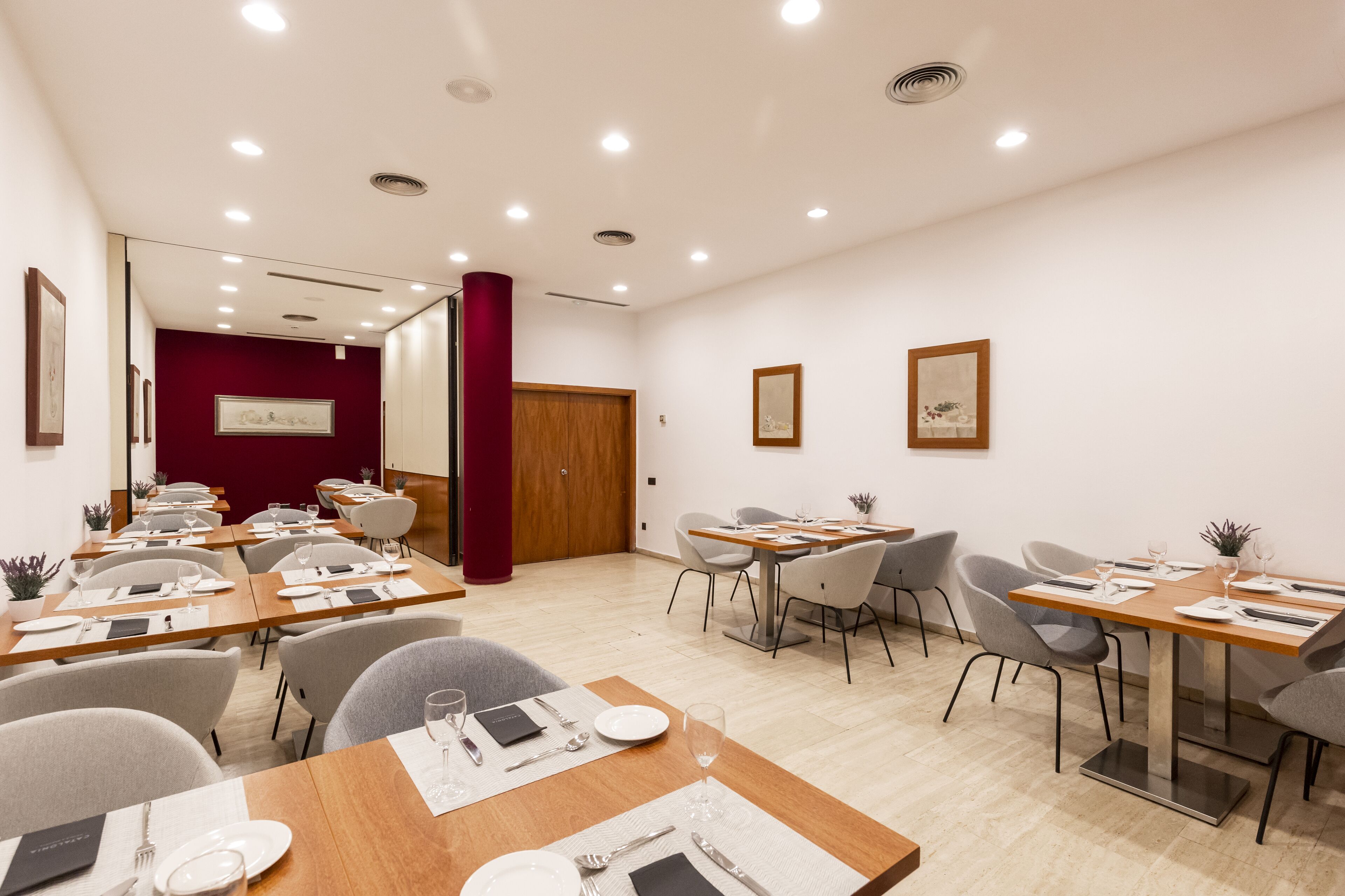 A modern conference room with multiple tables set for dining, equipped with chairs and dining essentials.