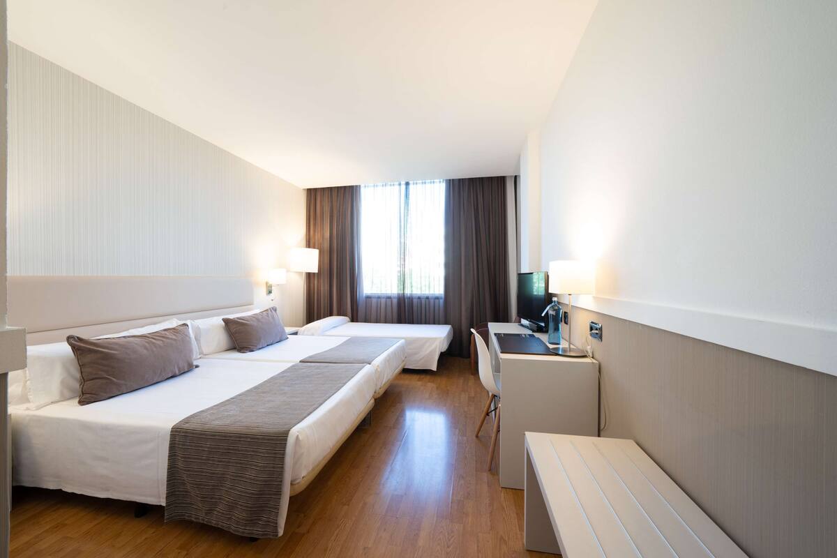 Een hotelkamer met twee bedden, een bureau, een stoel en een televisie.