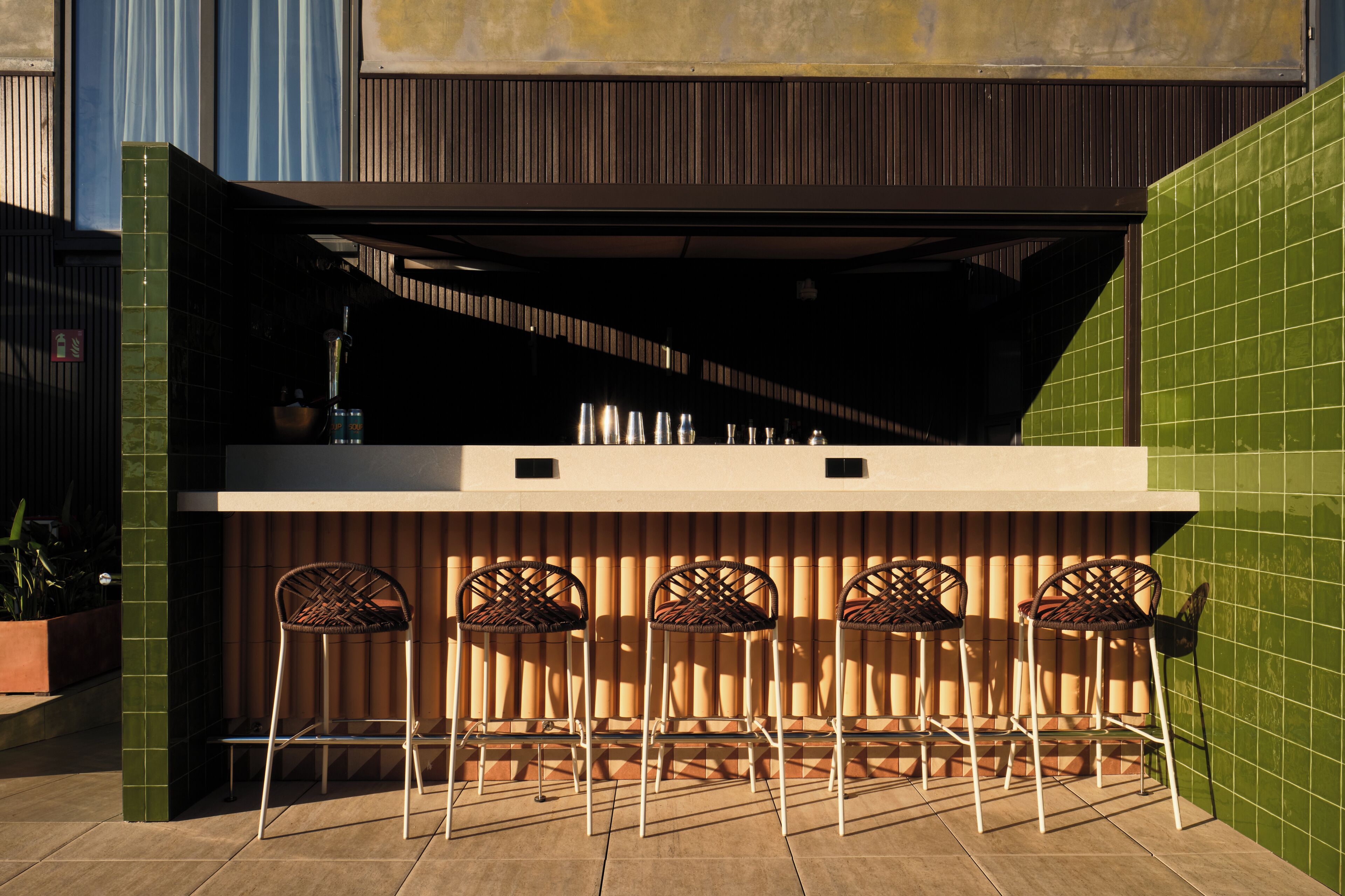 Un área de bar al aire libre con mostrador y cuatro sillas de mimbre.