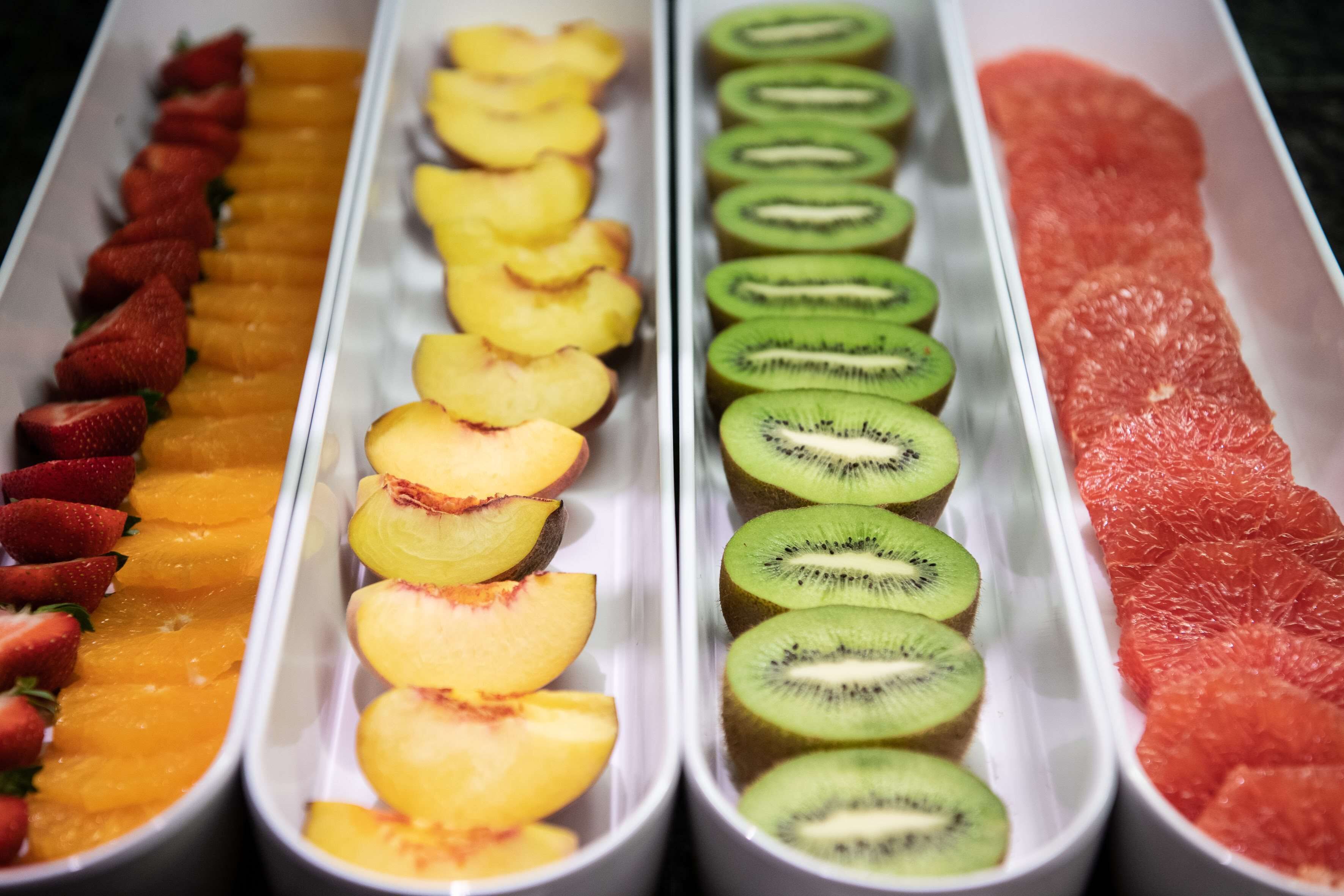 Presentació de fruita amb fresons tallats, pr éssecs, kiwi i pomelo.
