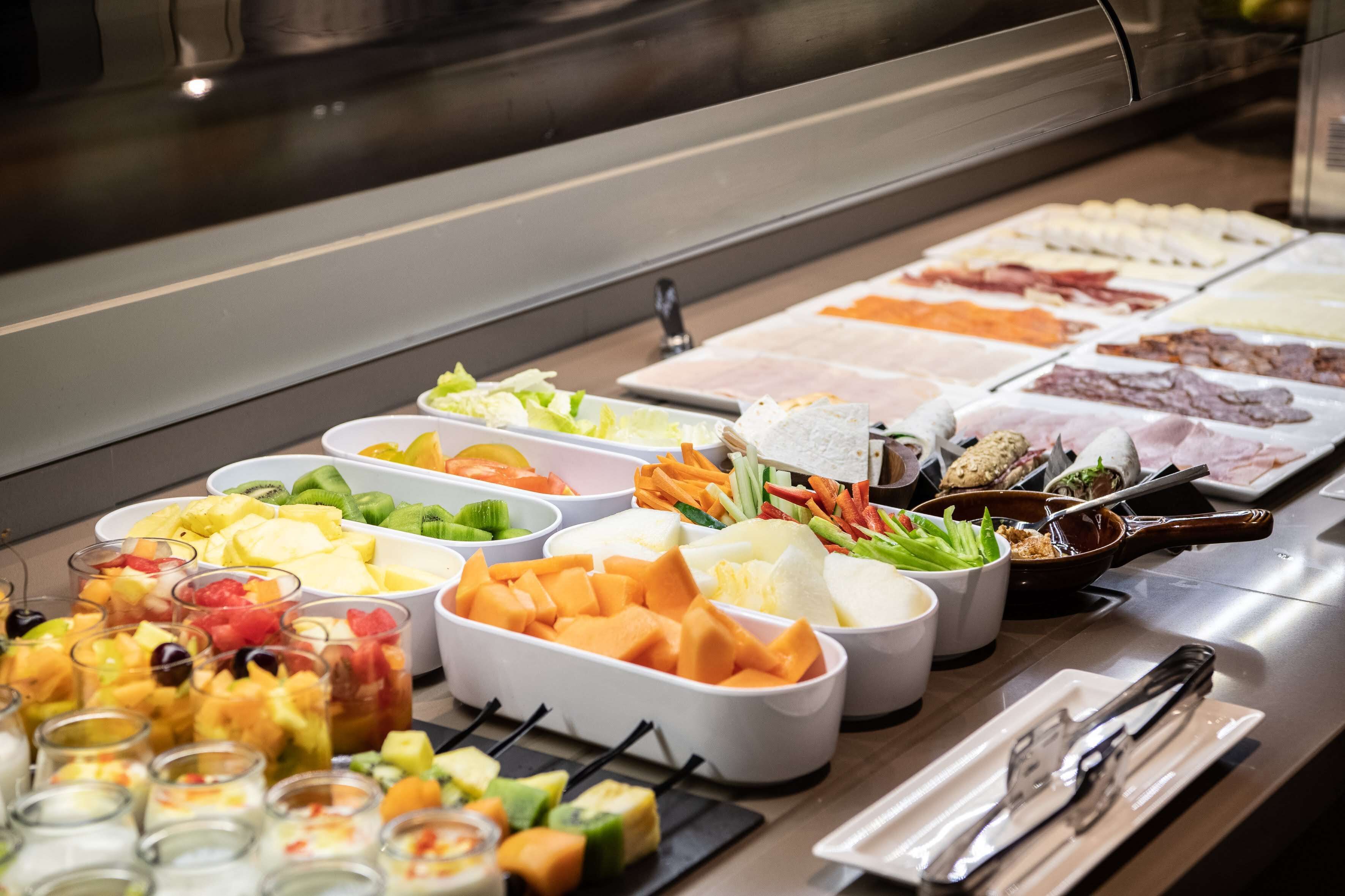 Een buffet met diverse gerechten, waaronder fruit, groenten, kazen en vlees.