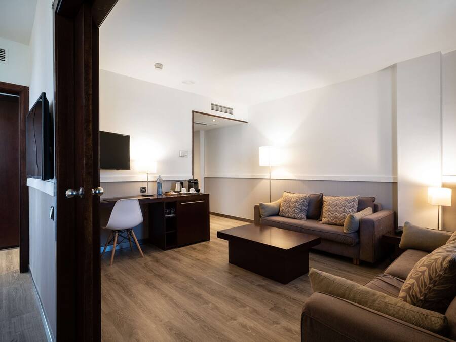 A modern living room with a sofa, coffee table, and a desk area with a chair.