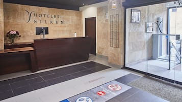 A hotel reception area with a reception desk, a TV, and a wall-mounted sign.