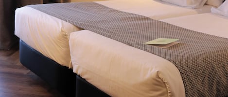 A hotel room with a bed, a nightstand, a lamp, and a curtain.
