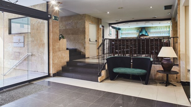 Un vestíbulo de hotel con una escalera, una zona de estar y una exhibición de botellas.