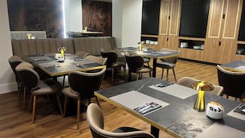 Un comedor moderno con varias mesas y sillas, armarios de madera y un detalle decorativo en la pared.