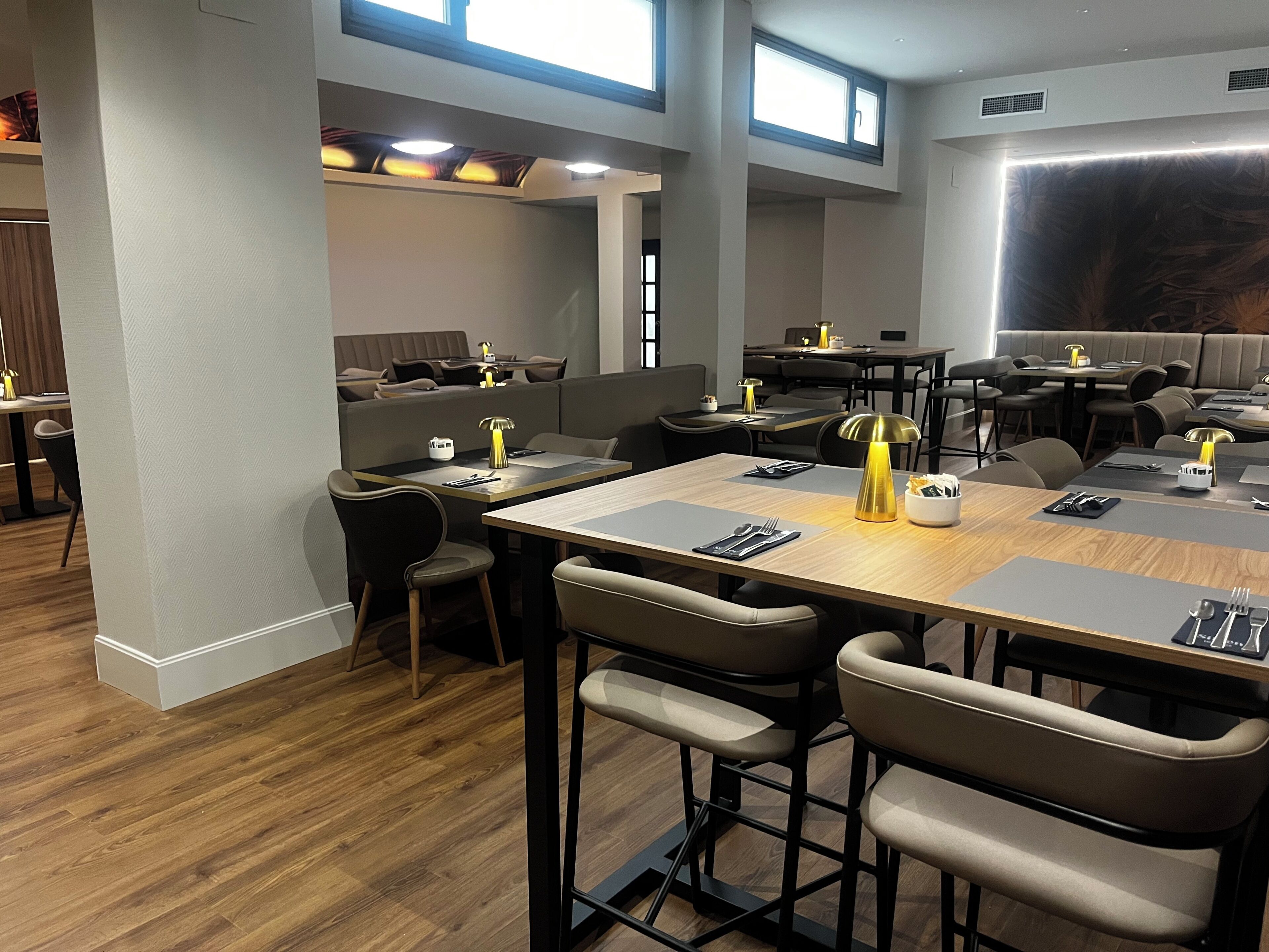 A modern restaurant with high tables, bar stools, and pendant lighting.