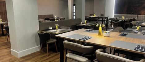 A modern restaurant with high tables, bar stools, and pendant lighting.