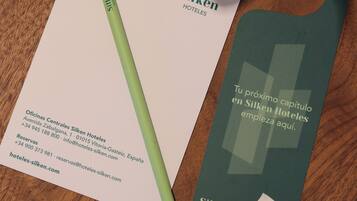 Een visitekaartje, een pen en een hotelnaamplaatje op een houten tafel.