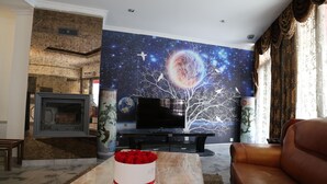Un salon avec une cheminée, un téléviseur à écran plat, un canapé et une fresque murale.