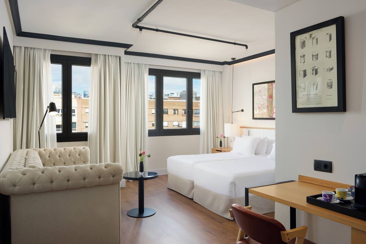 Une chambre d’hôtel avec un lit, un canapé, un bureau et une chaise.