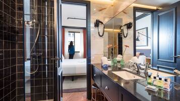 Een moderne badkamer met een douchecabine van glas, een grote spiegel en een wastafel met toiletartikelen.
