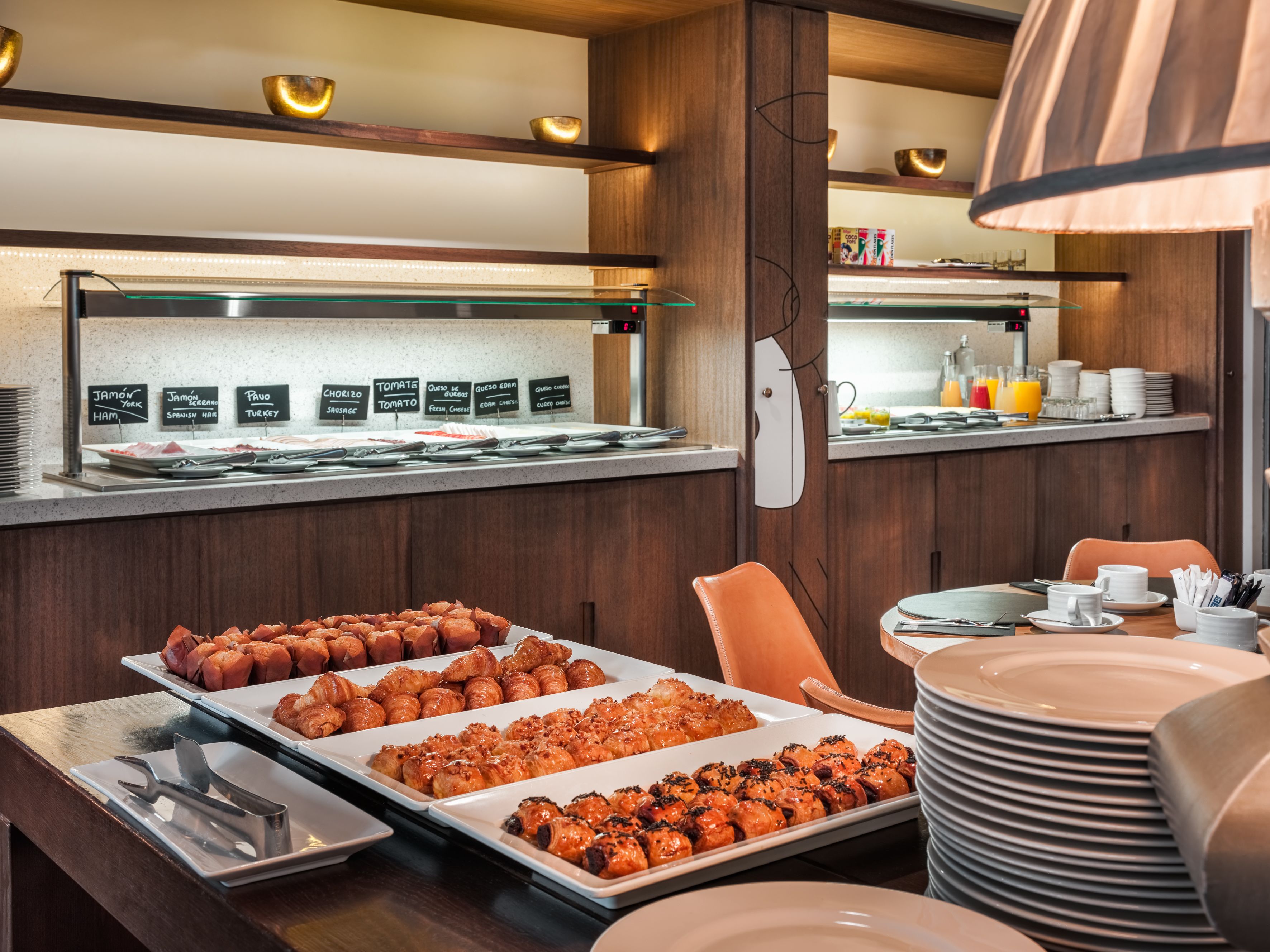 A buffet area with various food options and a seating area with a table set for dining.