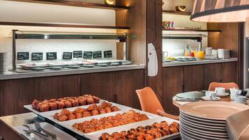Zona de bufé con diversas opciones de comida y un área de comedor con una mesa dispuesta.