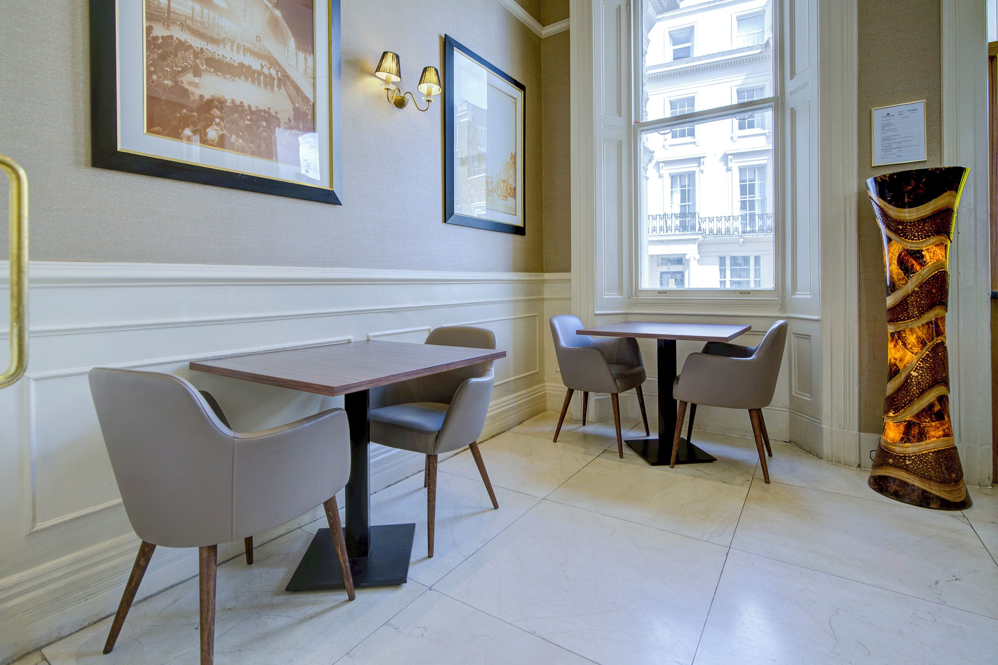 A dining area with a table and chairs, a framed picture on the wall, and a window with a view of buildings.
