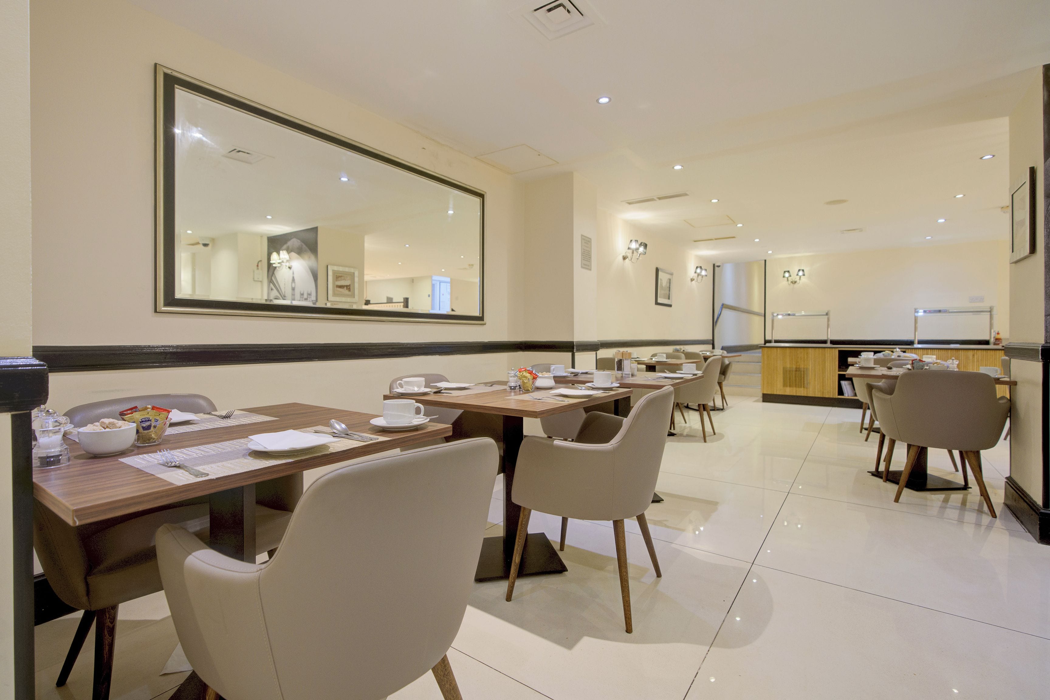 A dining area with tables, chairs, and a large mirror on the wall.