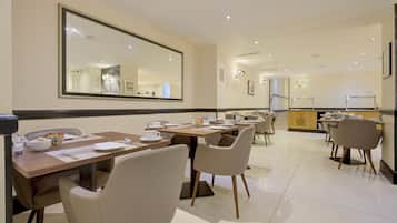 A dining area with tables, chairs, and a large mirror on the wall.