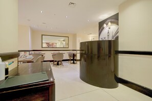 A hotel lobby with a reception desk, seating area, and a large mirror. - Sunday London Paddington Hotel (London)