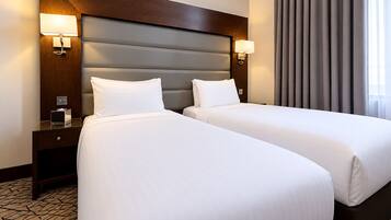 A hotel room with two beds, a wooden headboard, bedside lamps, and a patterned floor.