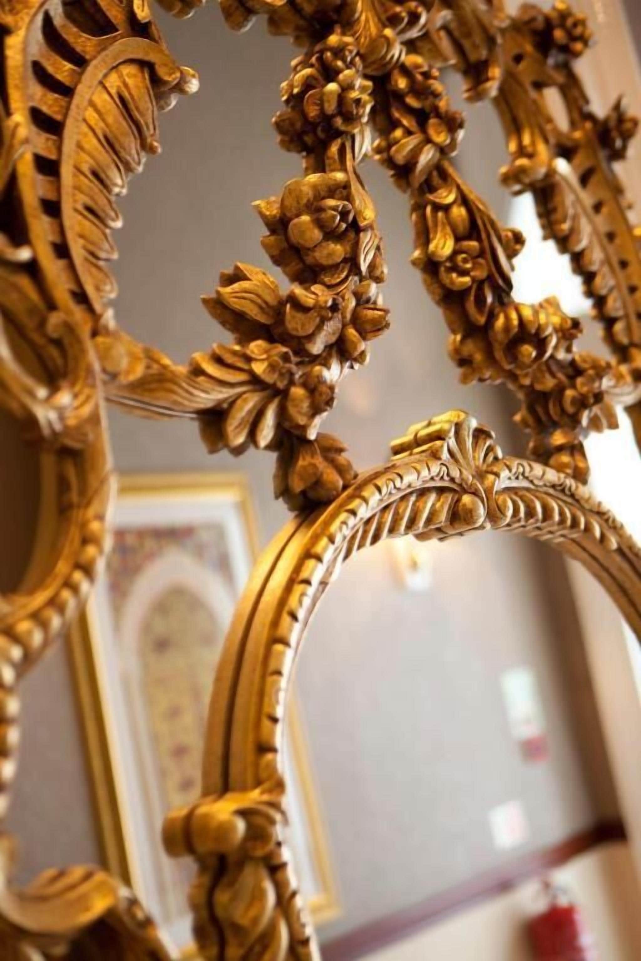 A close-up of an ornate, golden-framed mirror with intricate floral designs.
