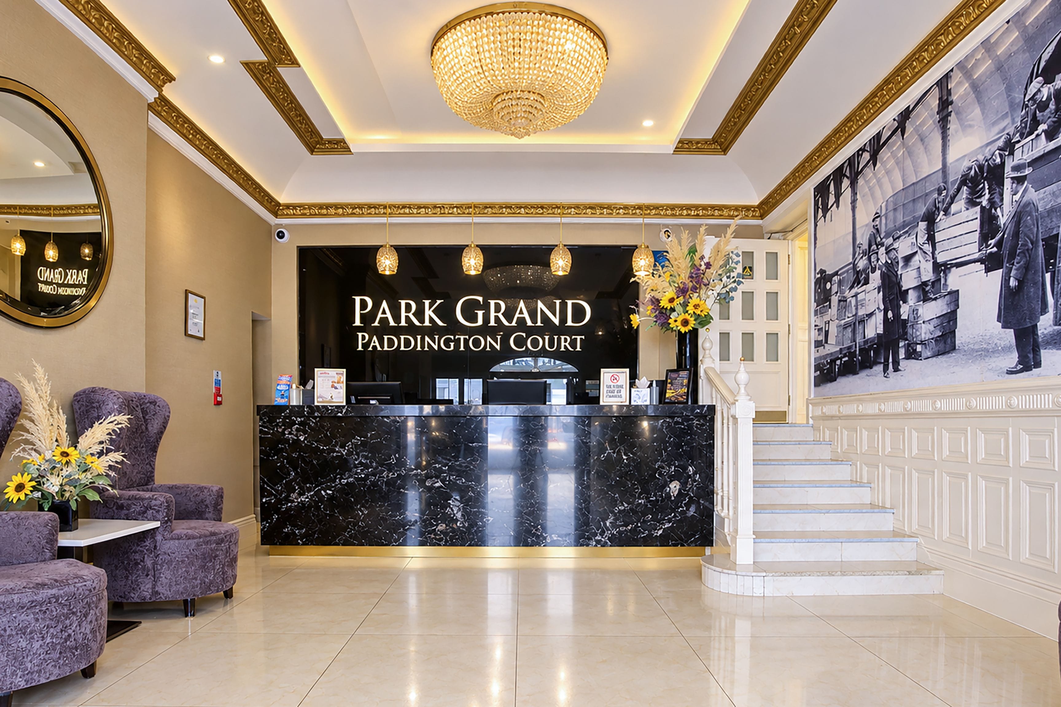 A reception area with a marble counter, a chandelier, and a framed historical photo on the wall.
