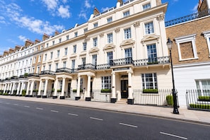 A row of traditional white buildings with black iron railings and a clear blue sky.