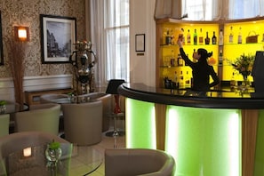 A bar area with a bartender, a green-lit bar counter, and a wall of liquor bottles. - Sunday London Paddington Hotel (London)