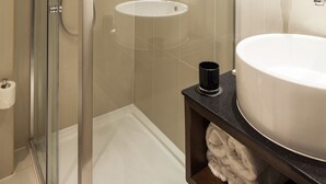 Ein modernes Badezimmer mit einer Duschkabine aus Glas, einem weißen Waschbecken und einem großen Spiegel.