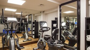 Ein Fitnessstudio mit Herz-Kreislauf-Geräten, Spiegeln und Trainingsausrüstung.