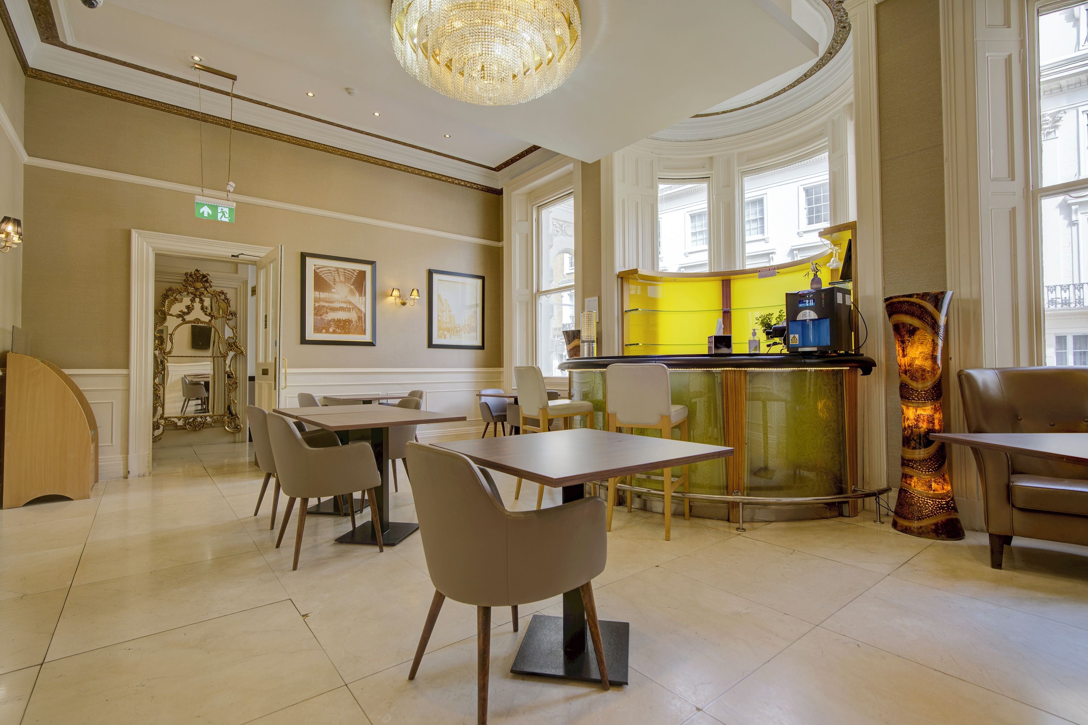 Un hall d’hôtel comprenant un bar, des espaces aménagés pour s’asseoir et des œuvres d’art encadrées accrochées aux murs.