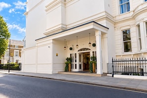 A white building with a classic architectural style, featuring a prominent entrance with a covered porch and a black wrought iron fence. - Sunday London Paddington Hotel (London)