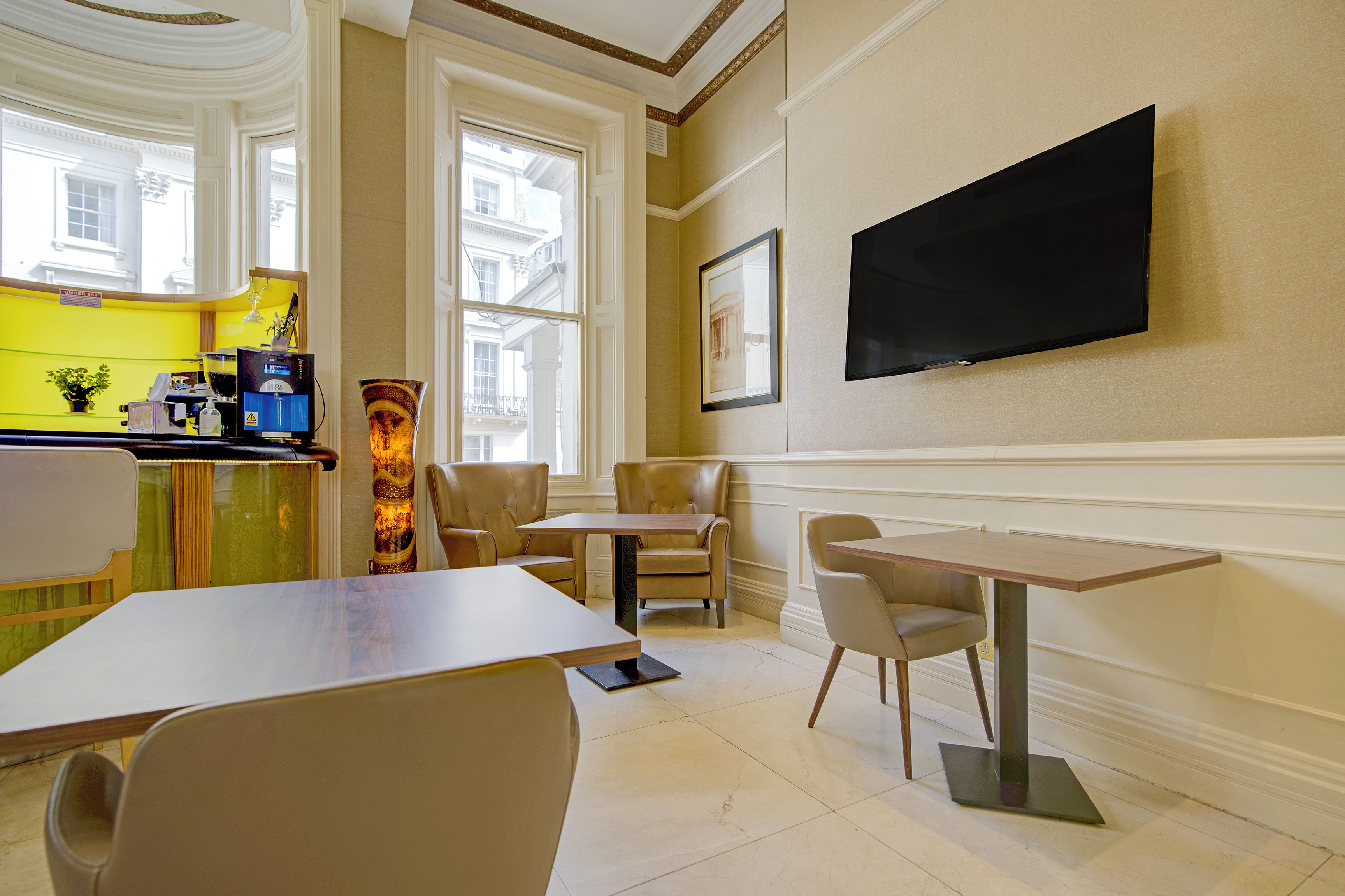Ein Hotelzimmer mit Essbereich, einer Bar und einem an der Wand befestigten Fernseher.