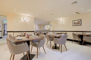 A hotel dining area with tables, chairs, and wall-mounted lighting. - Sunday London Paddington Hotel (London)