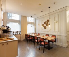 Un comedor con mesa y sillas de madera, mostrador de buffet y ventana con vistas a edificios.